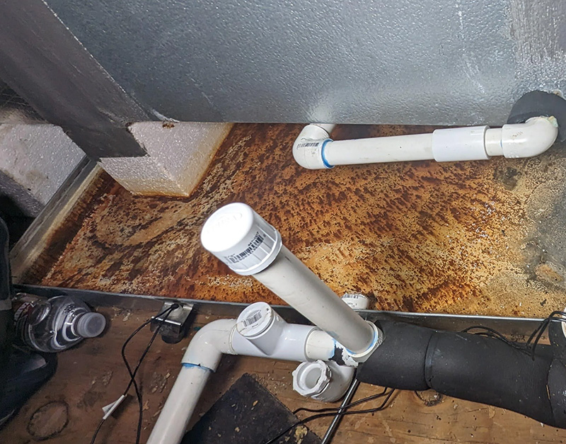 Corroded drain pan requiring cleaning and preparation before restoration
